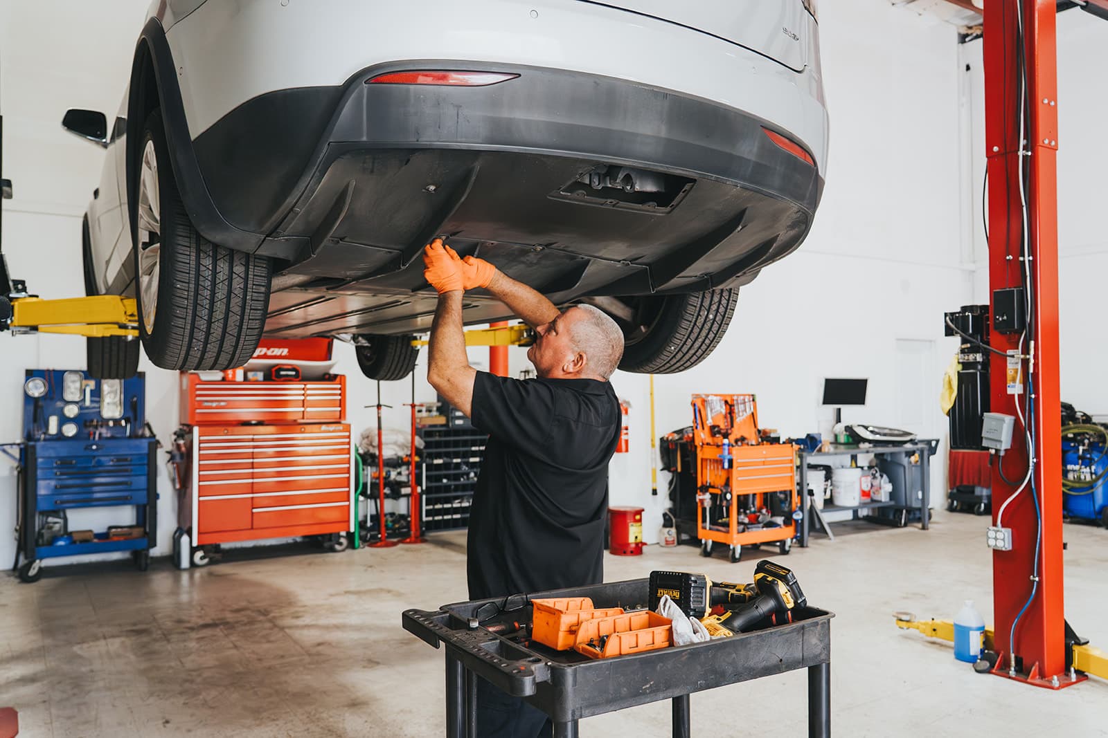 Technician servicing an electric vehicle raised on a lift in a professional workshop